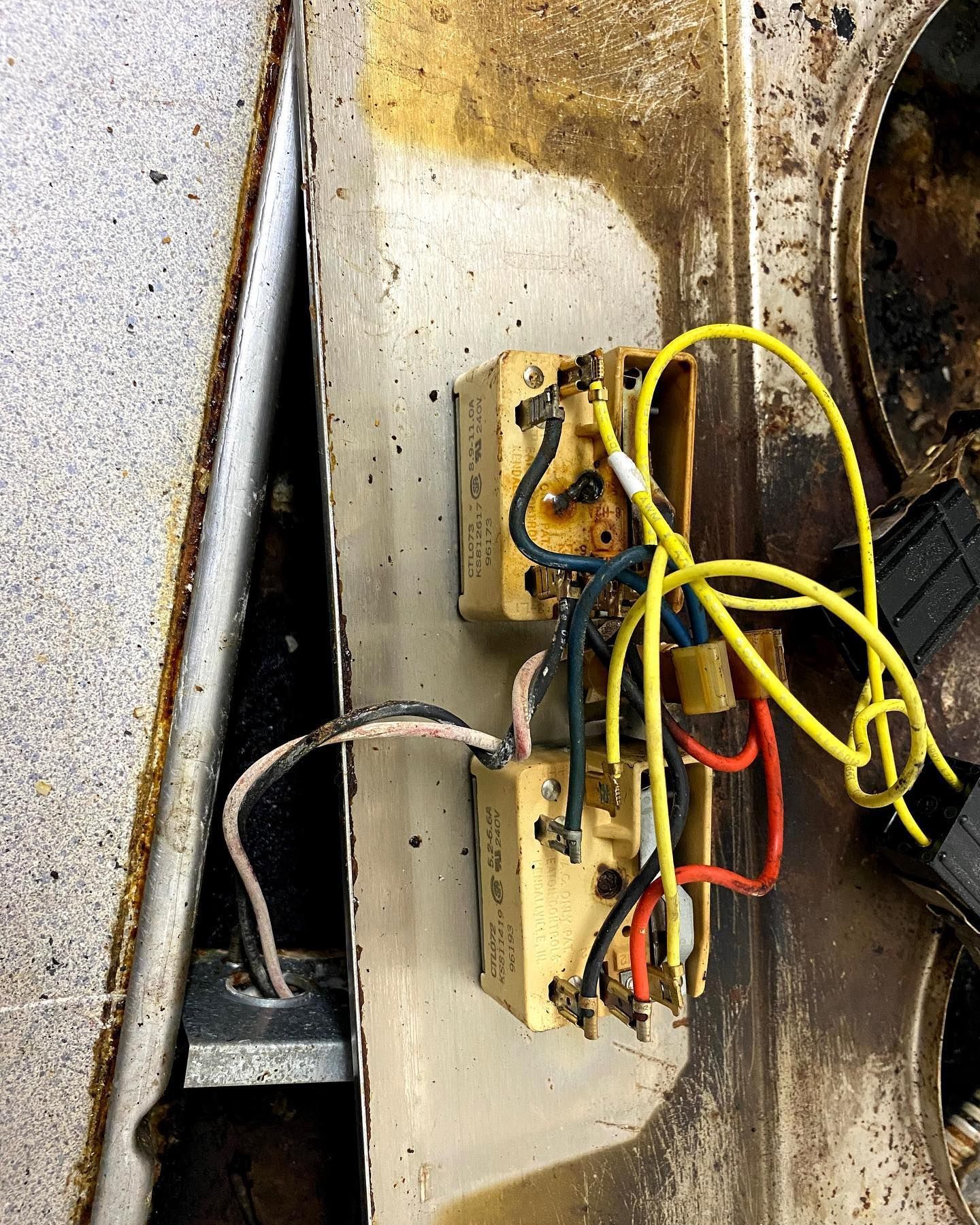 Burnt electrical components on a stovetop; charred wires, exposed connections.