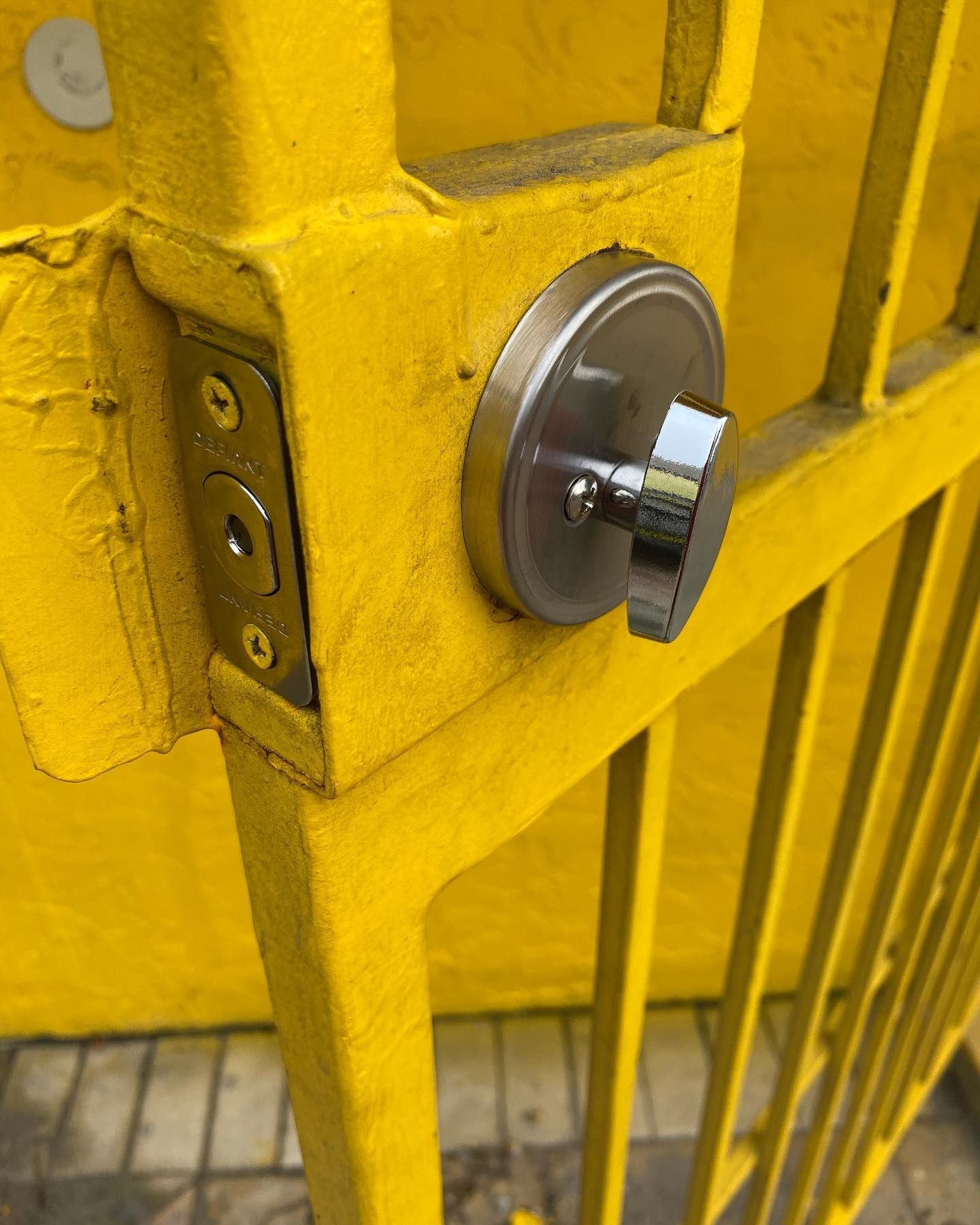Yellow metal gate with a silver door lock and handle.