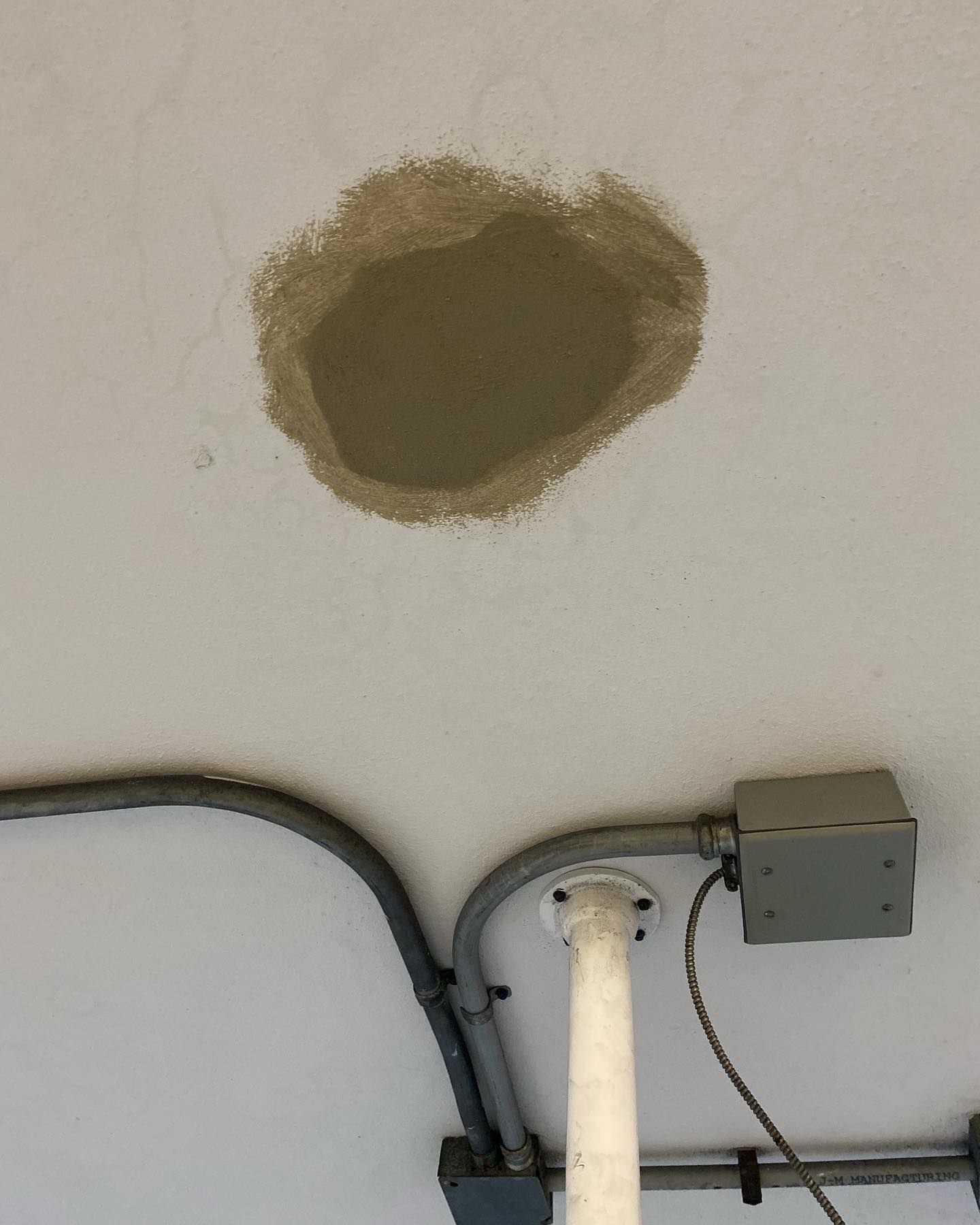 Ceiling with a repaired hole, conduits, and an electrical box.