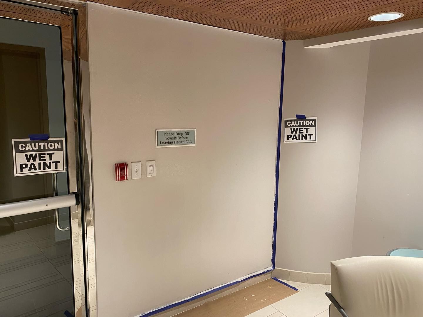 Room with wet paint; blue tape outlines a wall corner, 