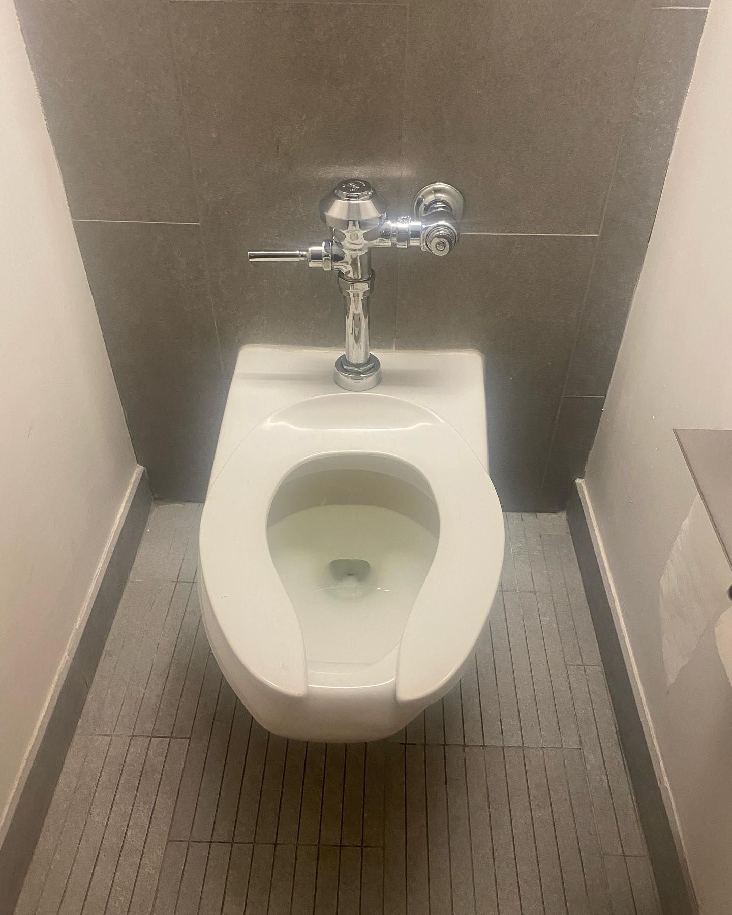 White toilet in a small bathroom. Grey walls and floor.