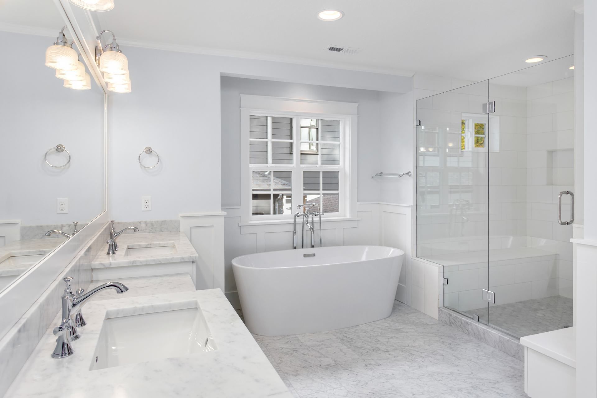 Bright white bathroom with a soaking tub, glass shower, and marble countertops.