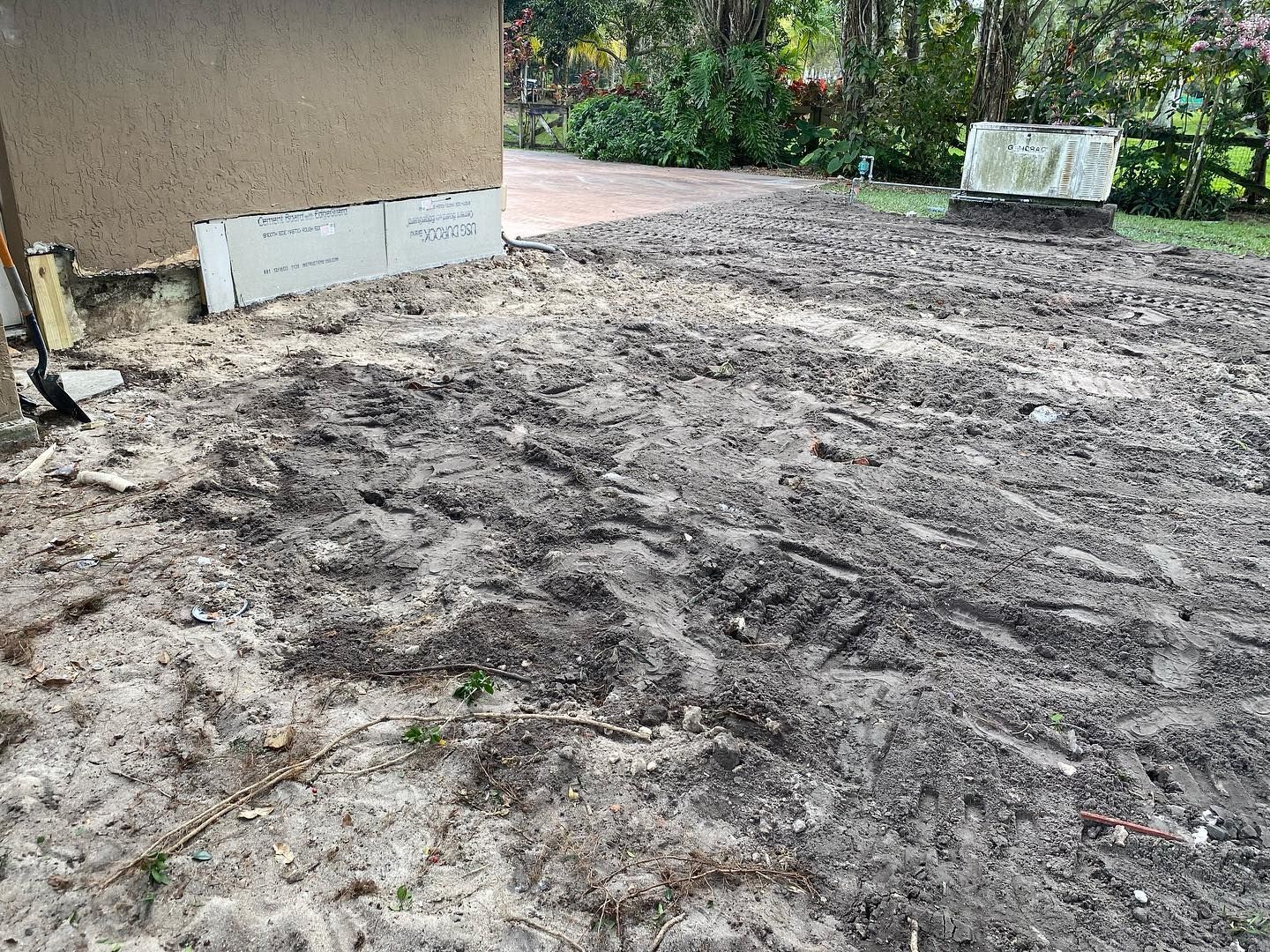 Dirt and sand ground with building and small concrete structure visible; outdoor setting.