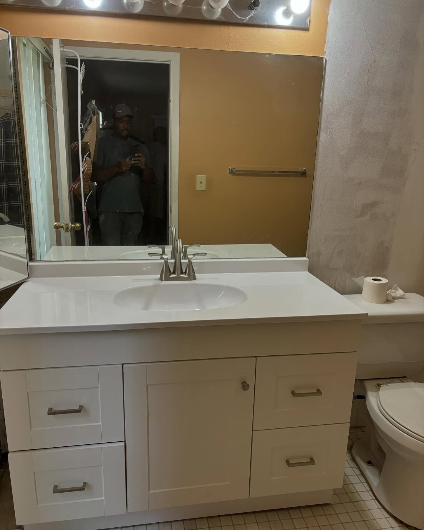 White bathroom vanity with a mirror, sink, and toilet.