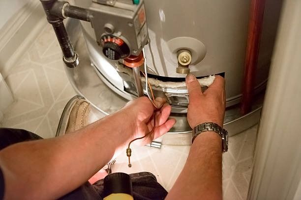 A man is fixing a water heater with a wrench.