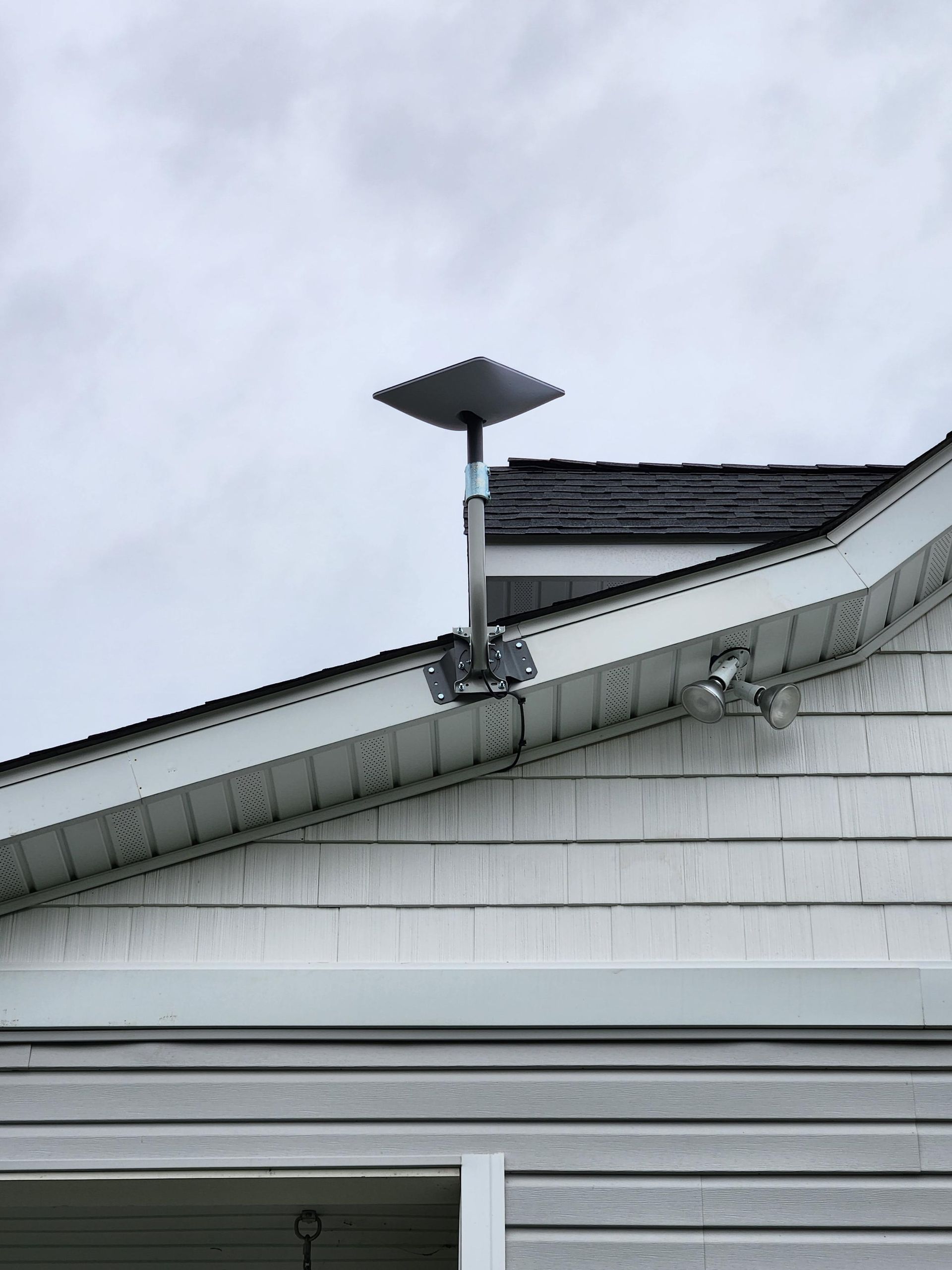 Small solar panel mounted on a house roof against a cloudy sky