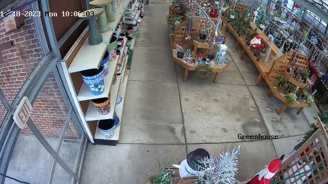 Overhead view of a storefront sidewalk with brick building, flower racks, and concrete walkway.