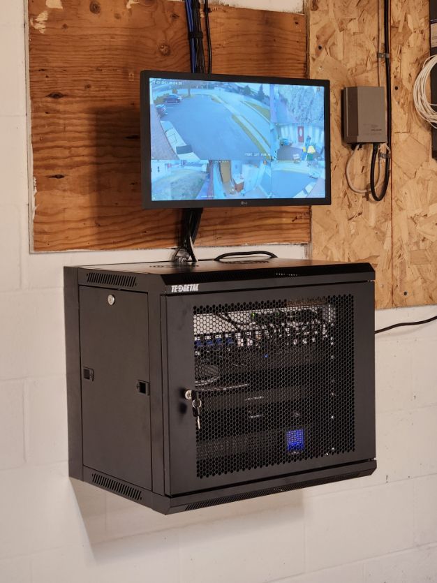 Wall-mounted monitor above a black security cabinet in a workshop-style room
