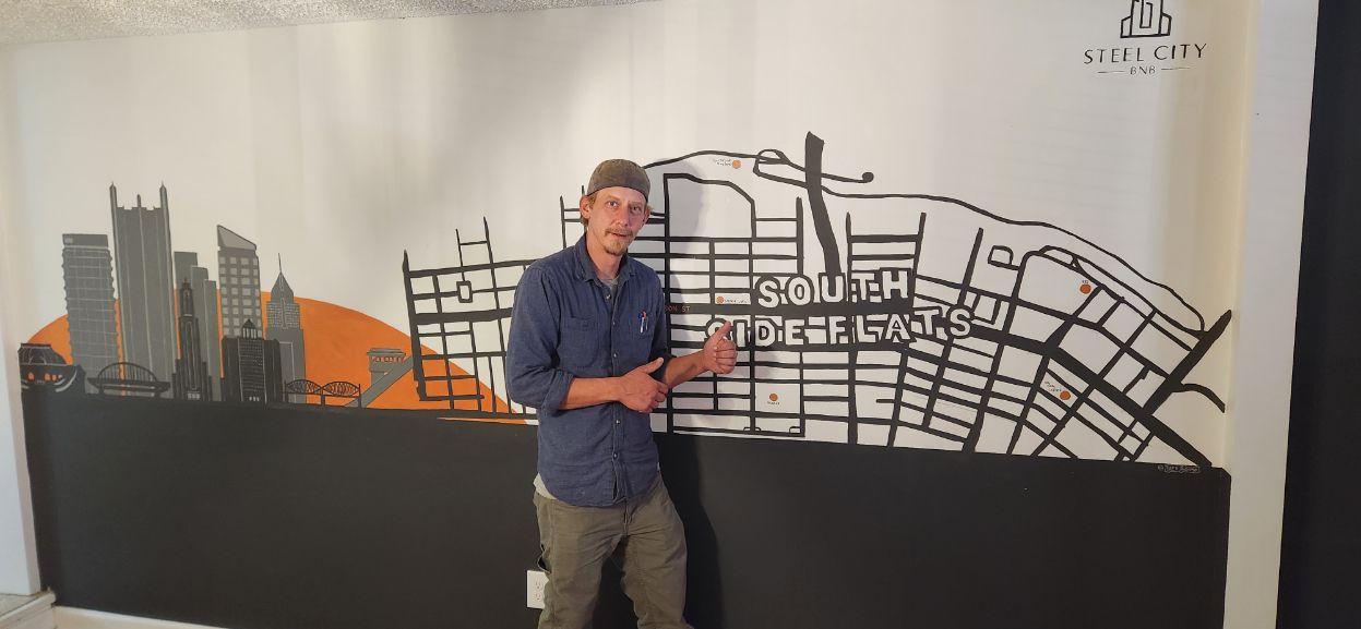 Person standing in front of a city map mural, pointing at the display