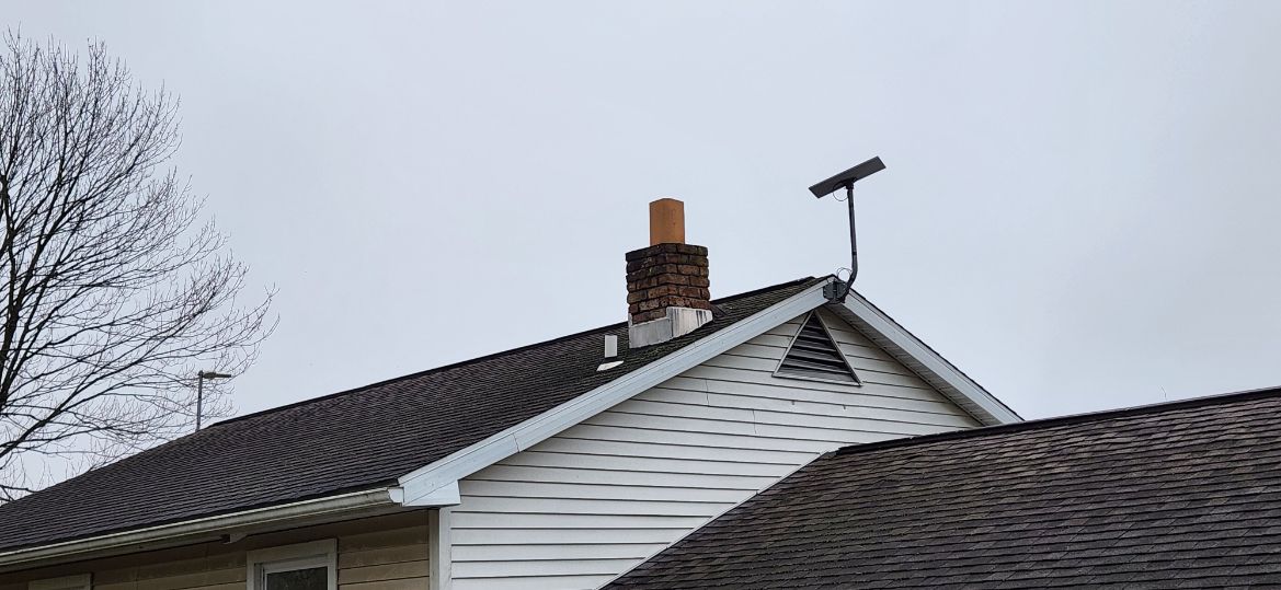 House roof with chimney and TV antenna under a cloudy sky