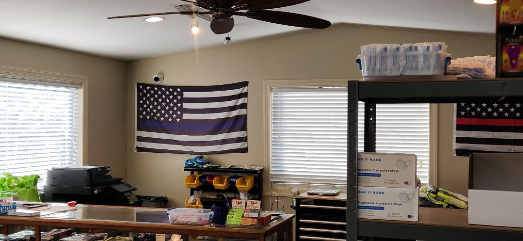 Office with U.S. flag wall art, desks, windows with blinds, and a ceiling fan.