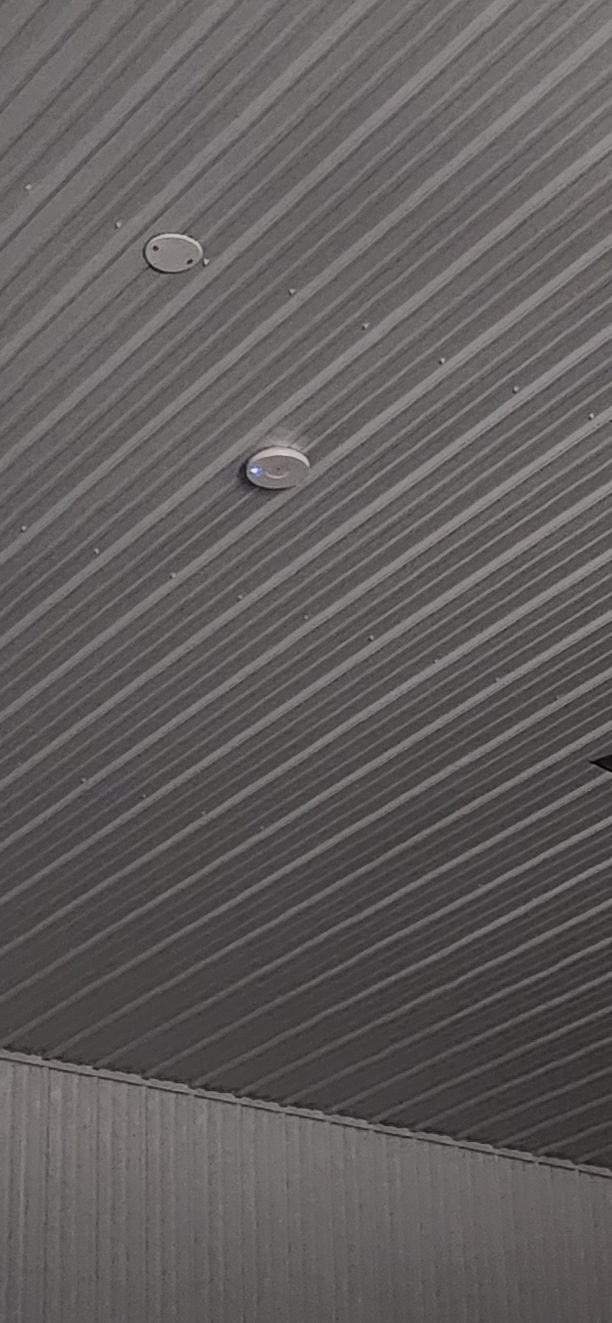 Two round ceiling lights on a gray, diagonally striped ceiling panel.