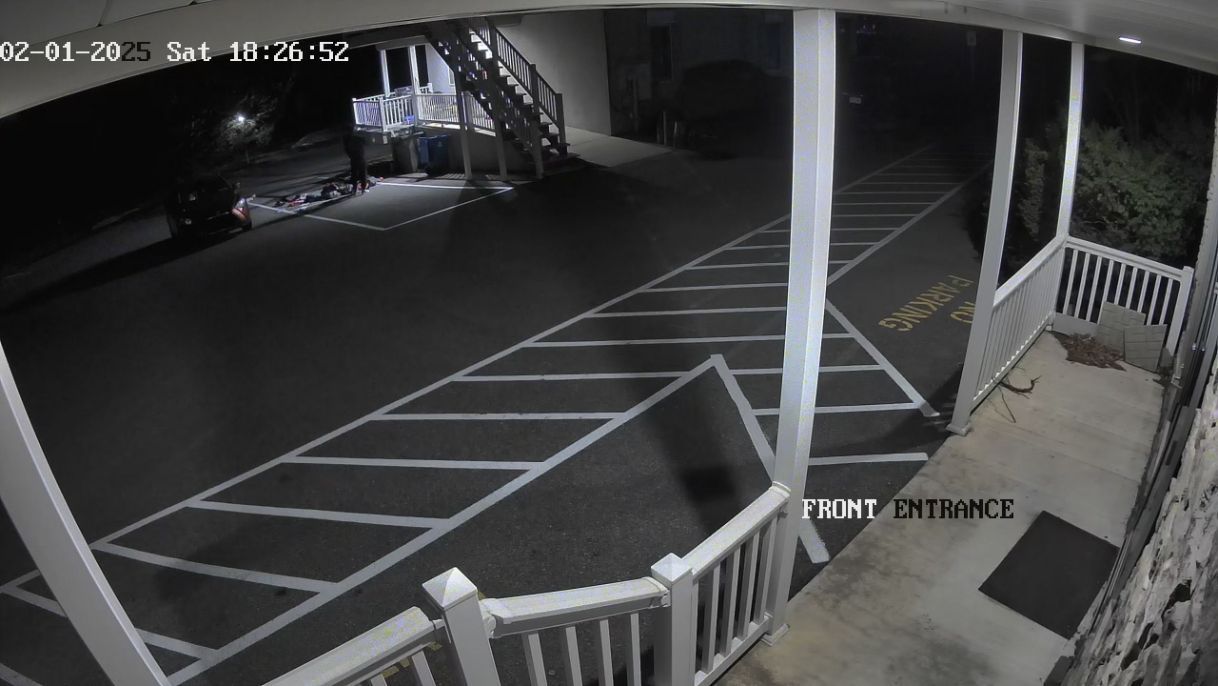 Empty parking lot at night, viewed from a porch with railings and a staircase.
