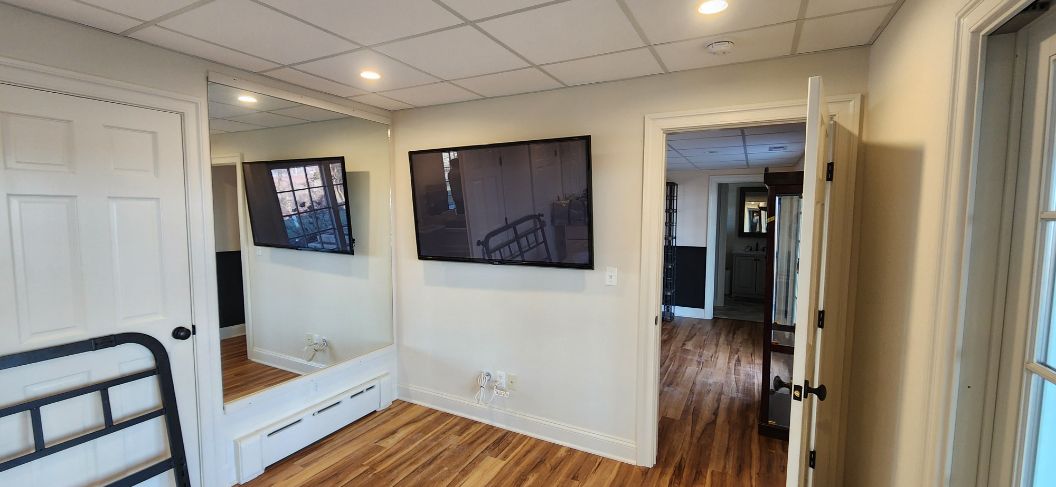 Bright bedroom with hardwood floors, twin beds, wall art, and a doorway to a hallway and bathroom
