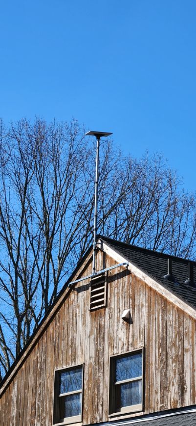 Wooden house gable with two windows and a roof vent against a clear blue sky