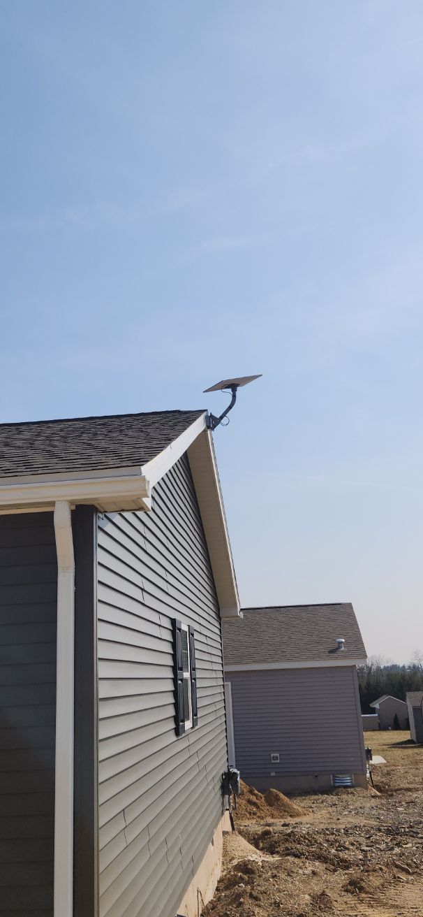 Seagull perched on a rooftop beside gray vinyl-sided houses under a clear sky