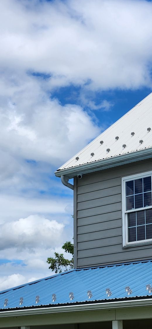 Gray house with blue roof under a cloudy sky