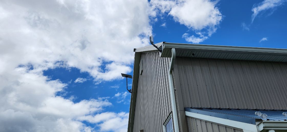 Gray industrial building corner under a bright blue sky with scattered white clouds