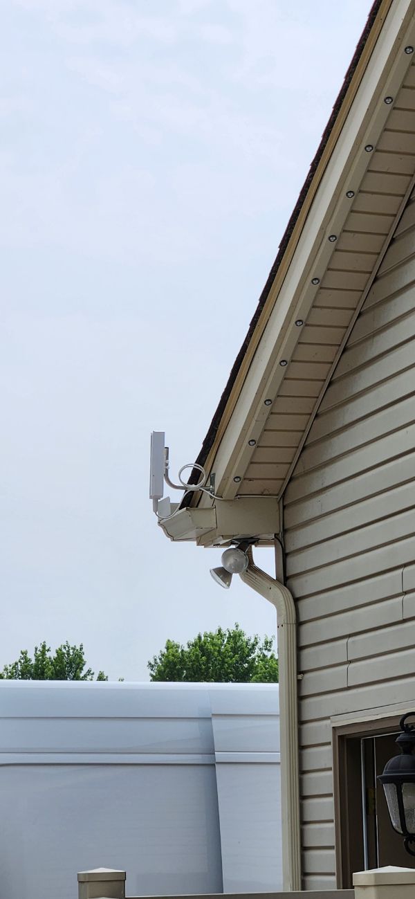 House exterior with white siding, roof eaves, and a satellite dish against the sky