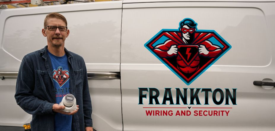 Man standing beside a white van with a red-and-black Franken Security logo and text.