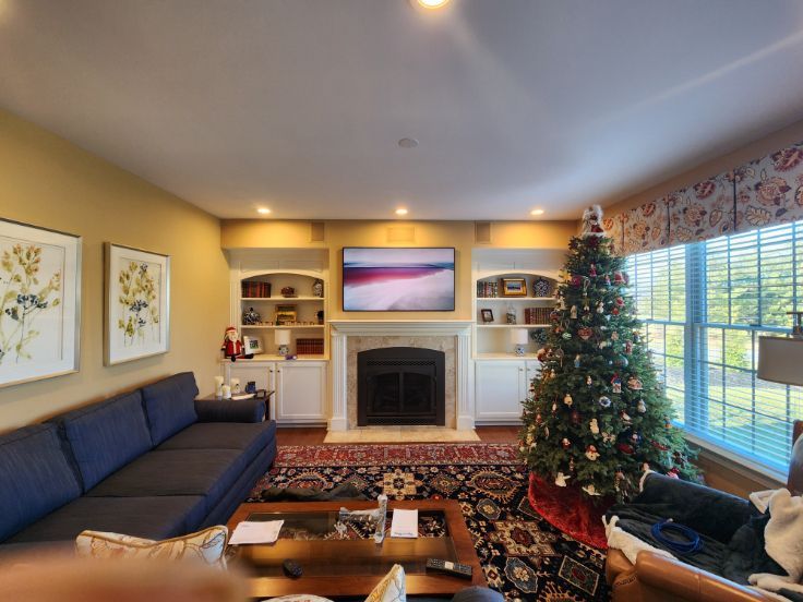 Cozy living room with fireplace, Christmas tree, blue sofa, and large window with blinds