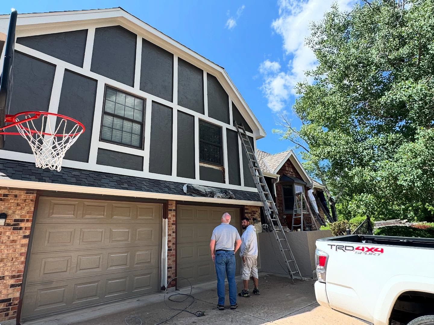 Two men are standing in front of a house that is being painted.