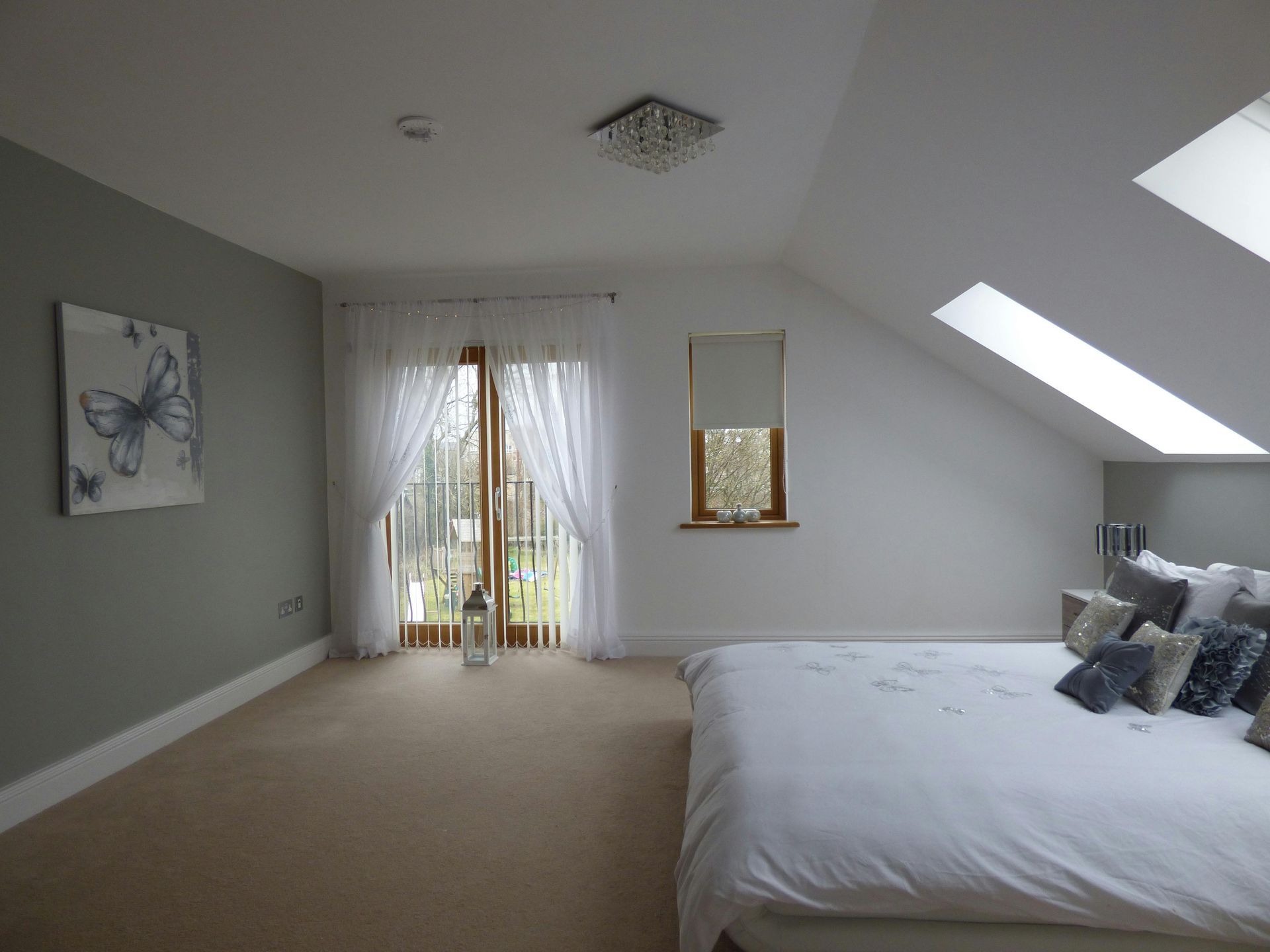 A bedroom with a bed , sliding glass doors , and a skylight.
