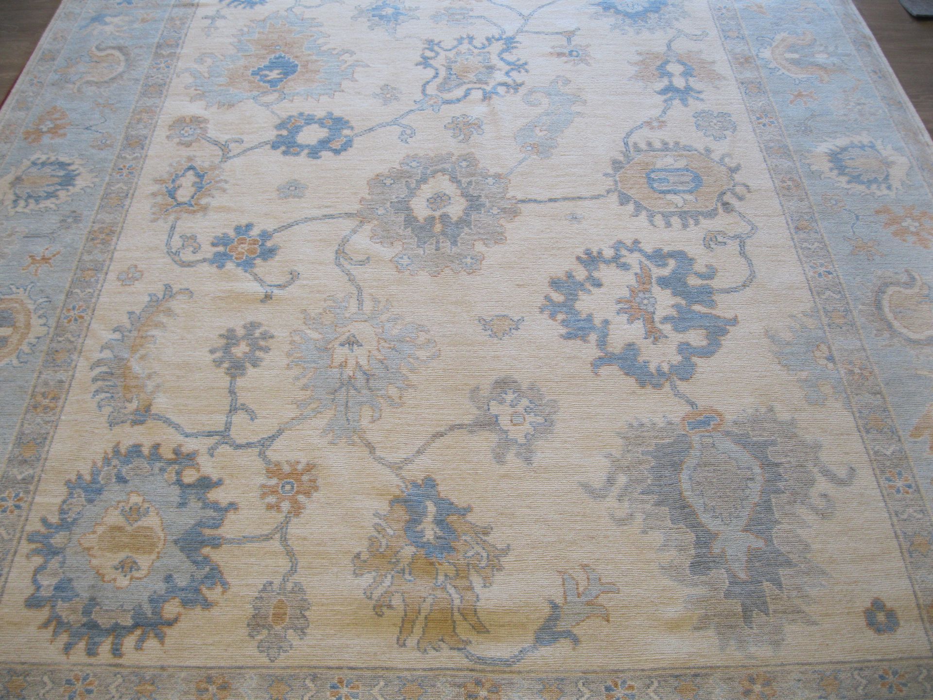 A rug with a floral pattern on it is sitting on a wooden floor.