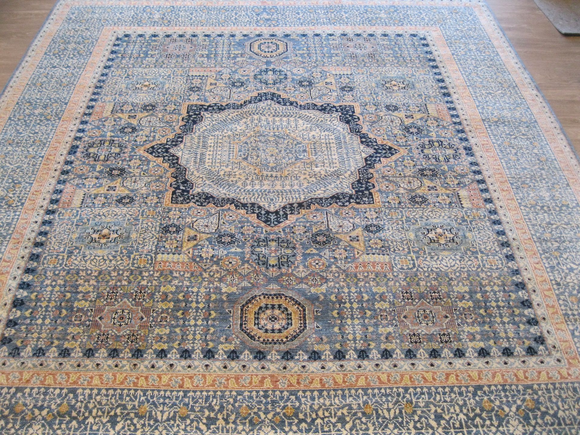 A large rug is sitting on a wooden floor.