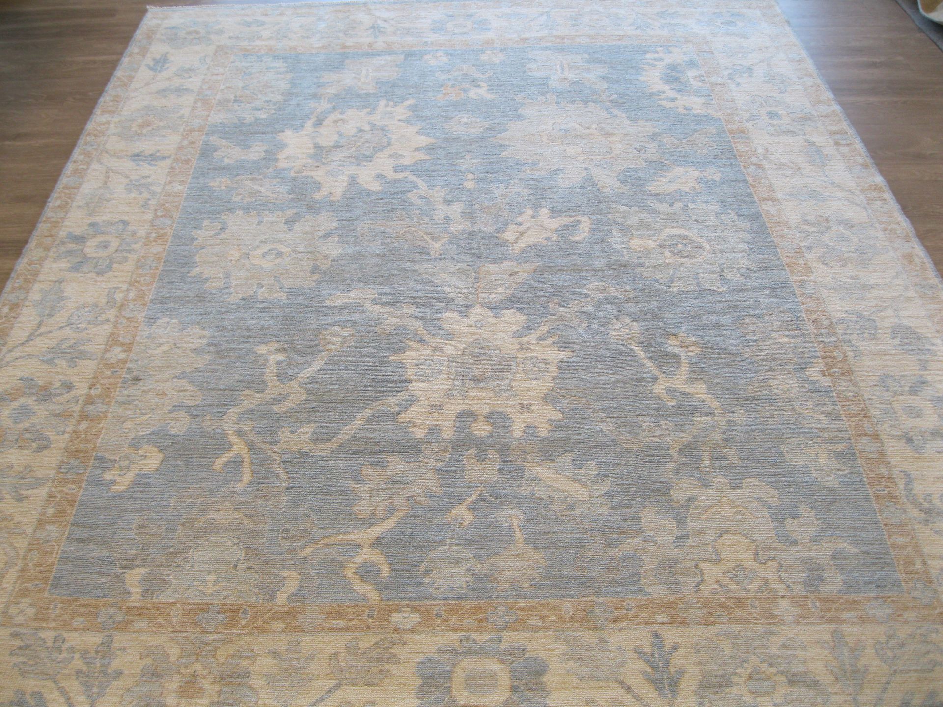 A large rug is sitting on a wooden floor.