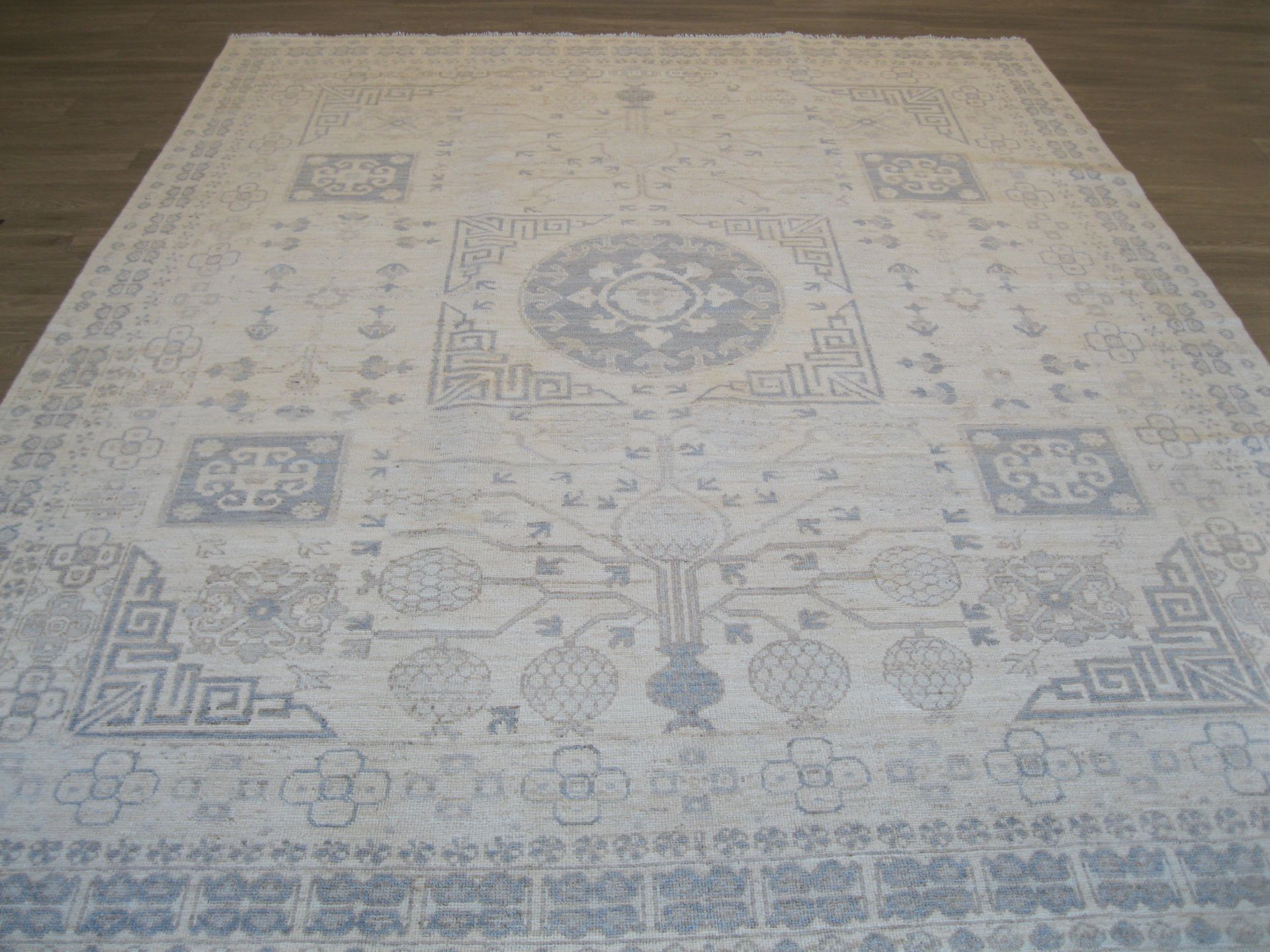 A white rug with a pattern on it is sitting on a wooden floor.