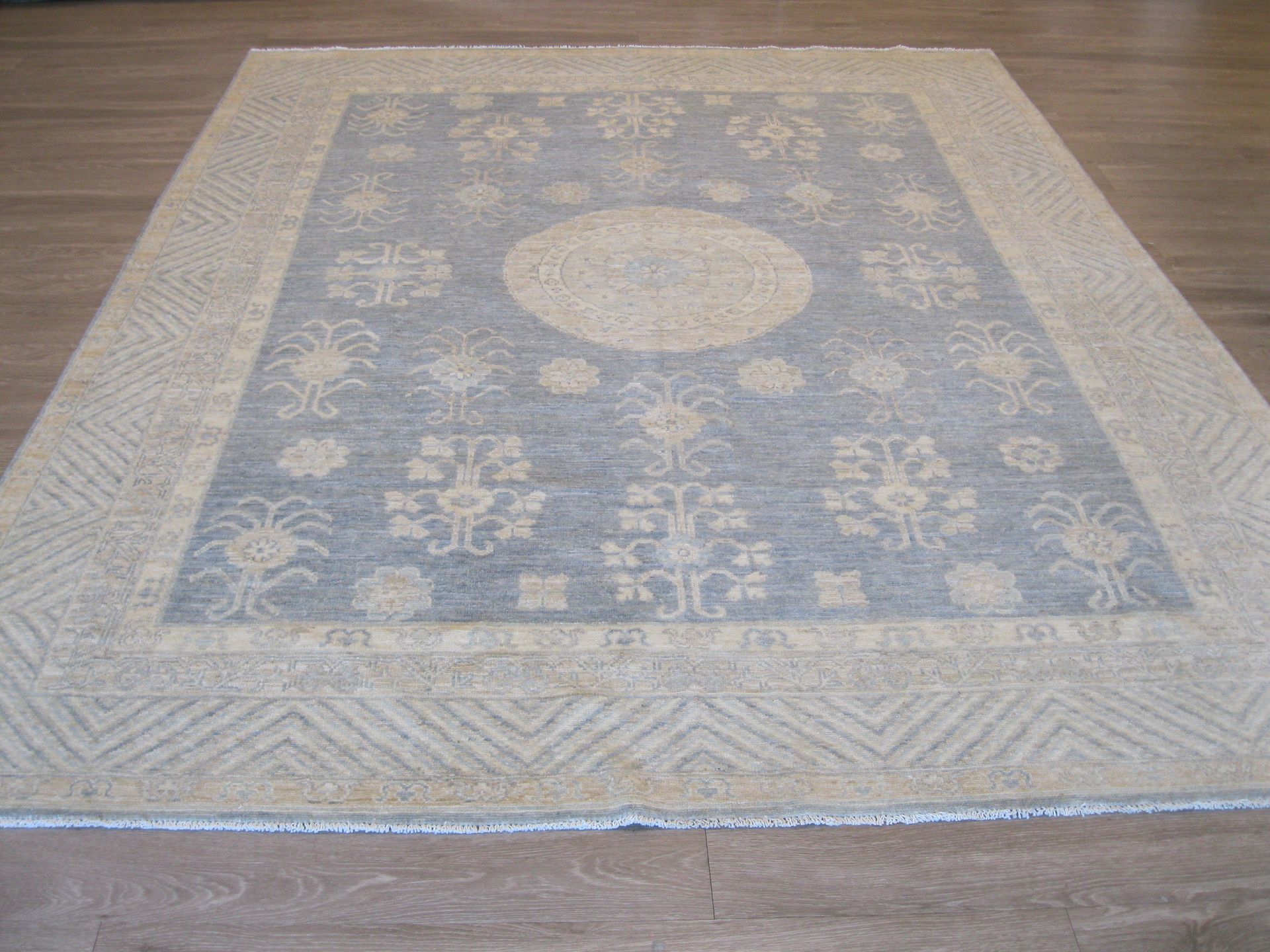 A rug with a pattern on it is sitting on a wooden floor.