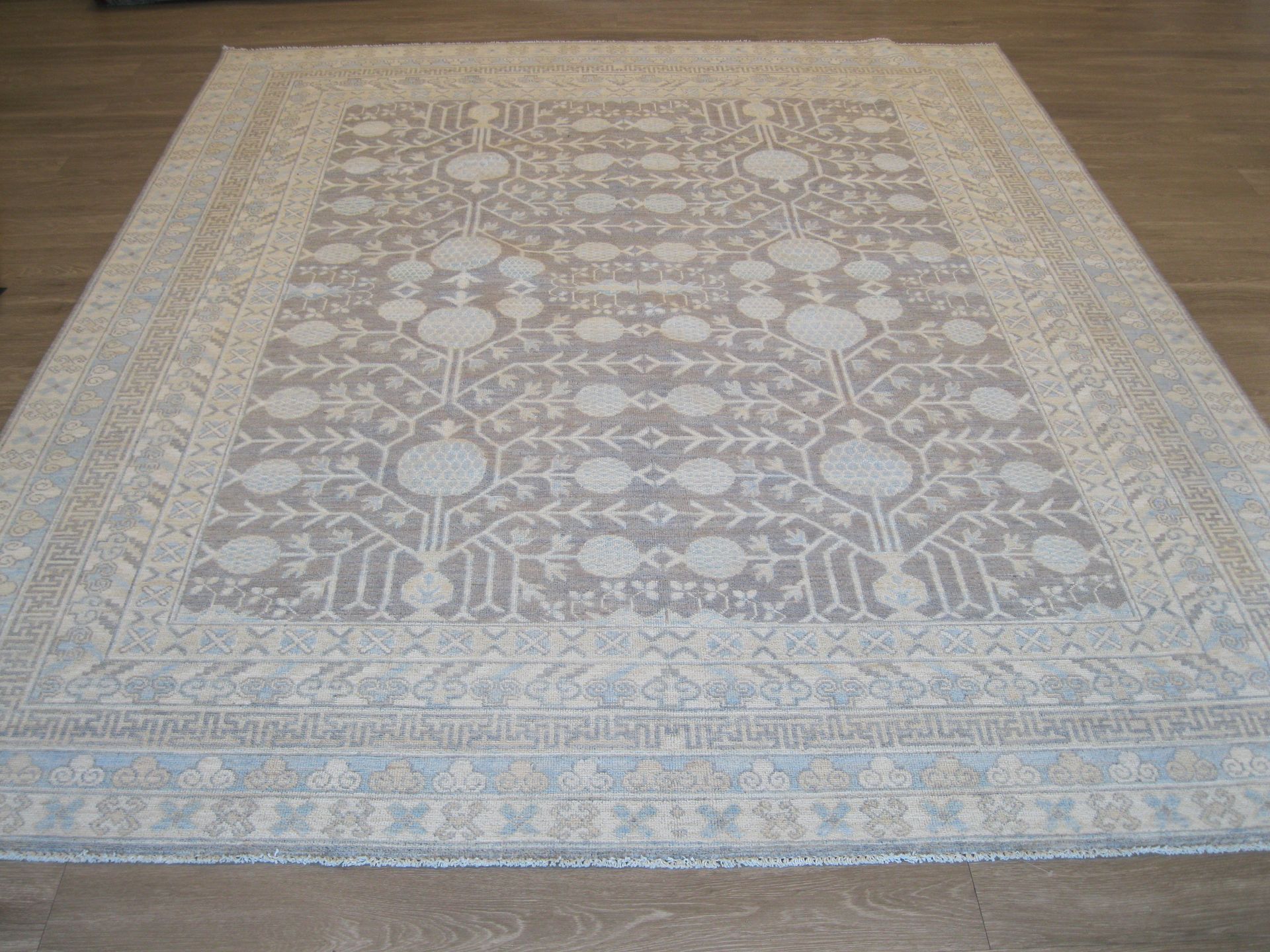 A white rug with a pattern on it is sitting on a wooden floor.