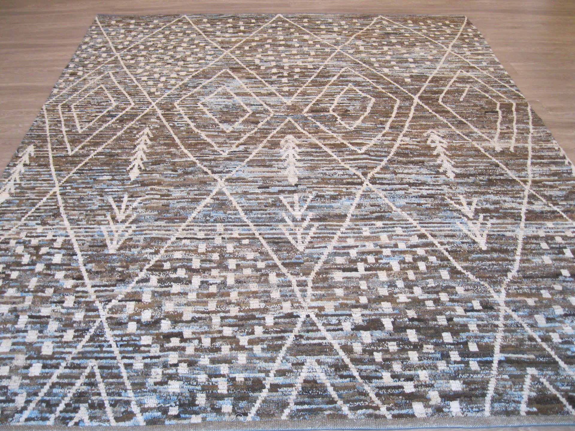 A rug with a geometric pattern is sitting on a wooden floor.