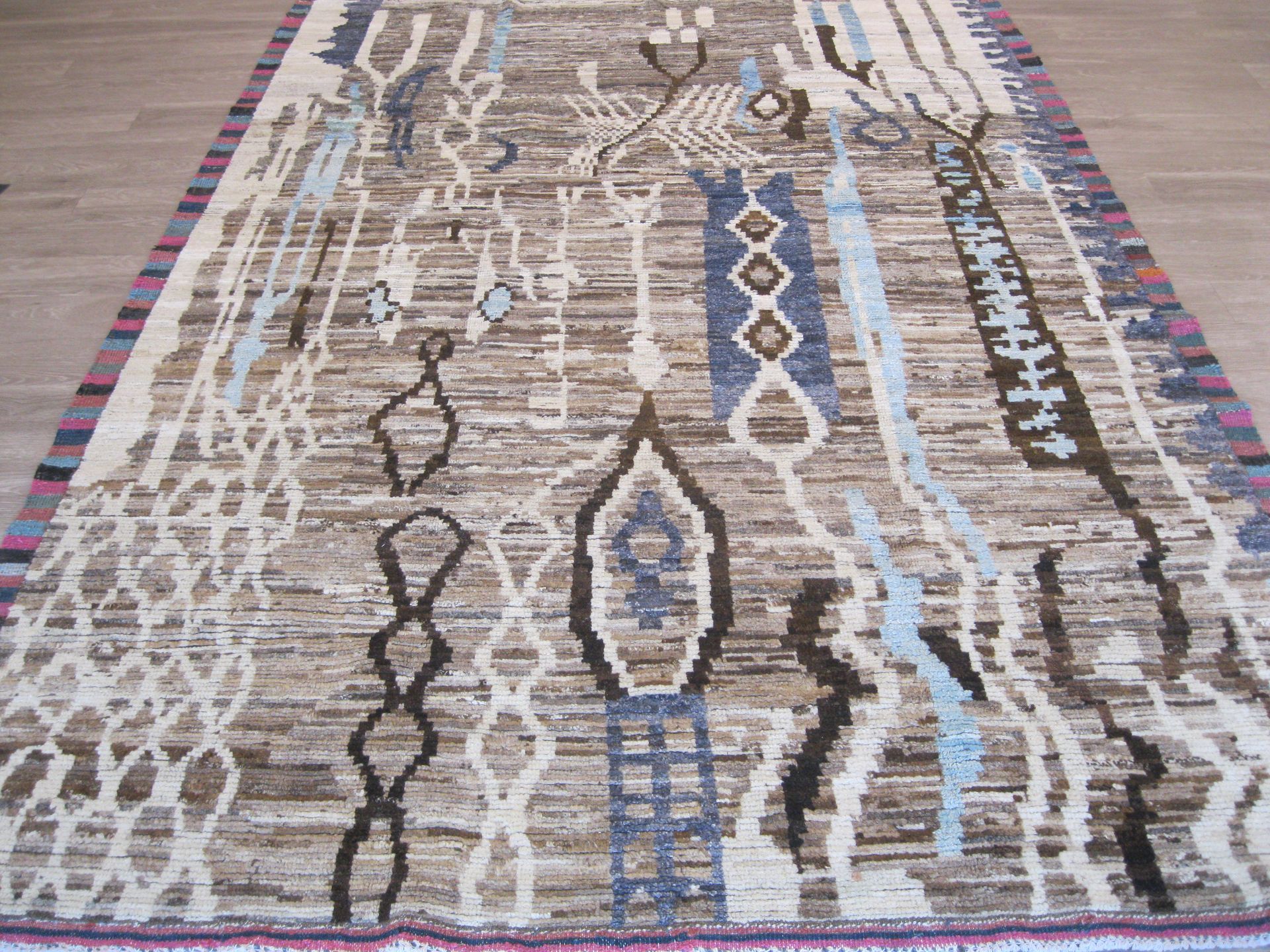 A rug with a pattern on it is sitting on a wooden floor.