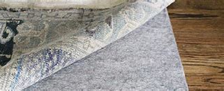 A black rug is sitting on a wooden floor.