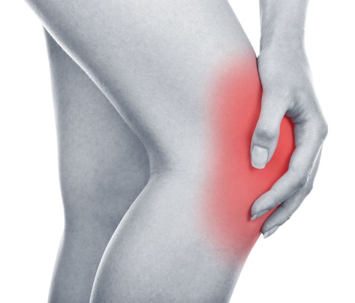 a woman is holding her knee in pain