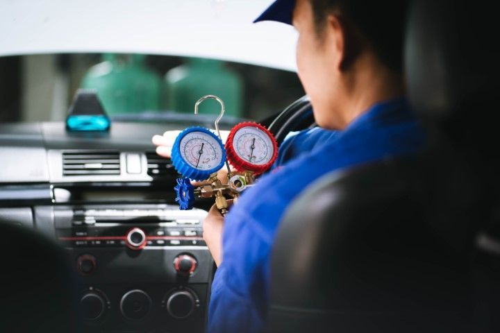A man is sitting in a car holding two gauges.