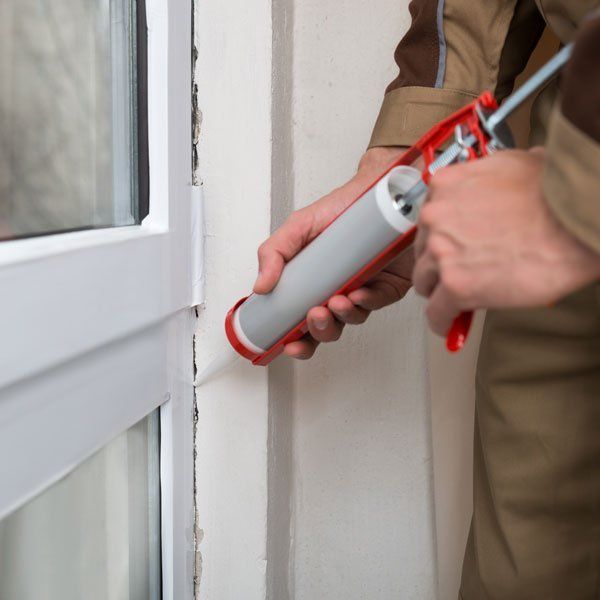 A person is applying silicone to the edge of door