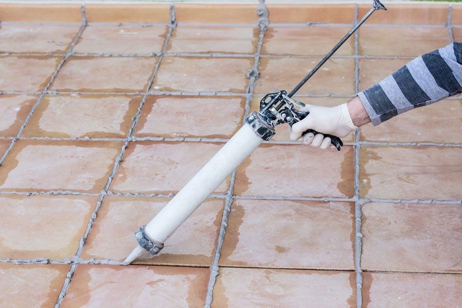 A person is applying silicone to the driveway asphalt