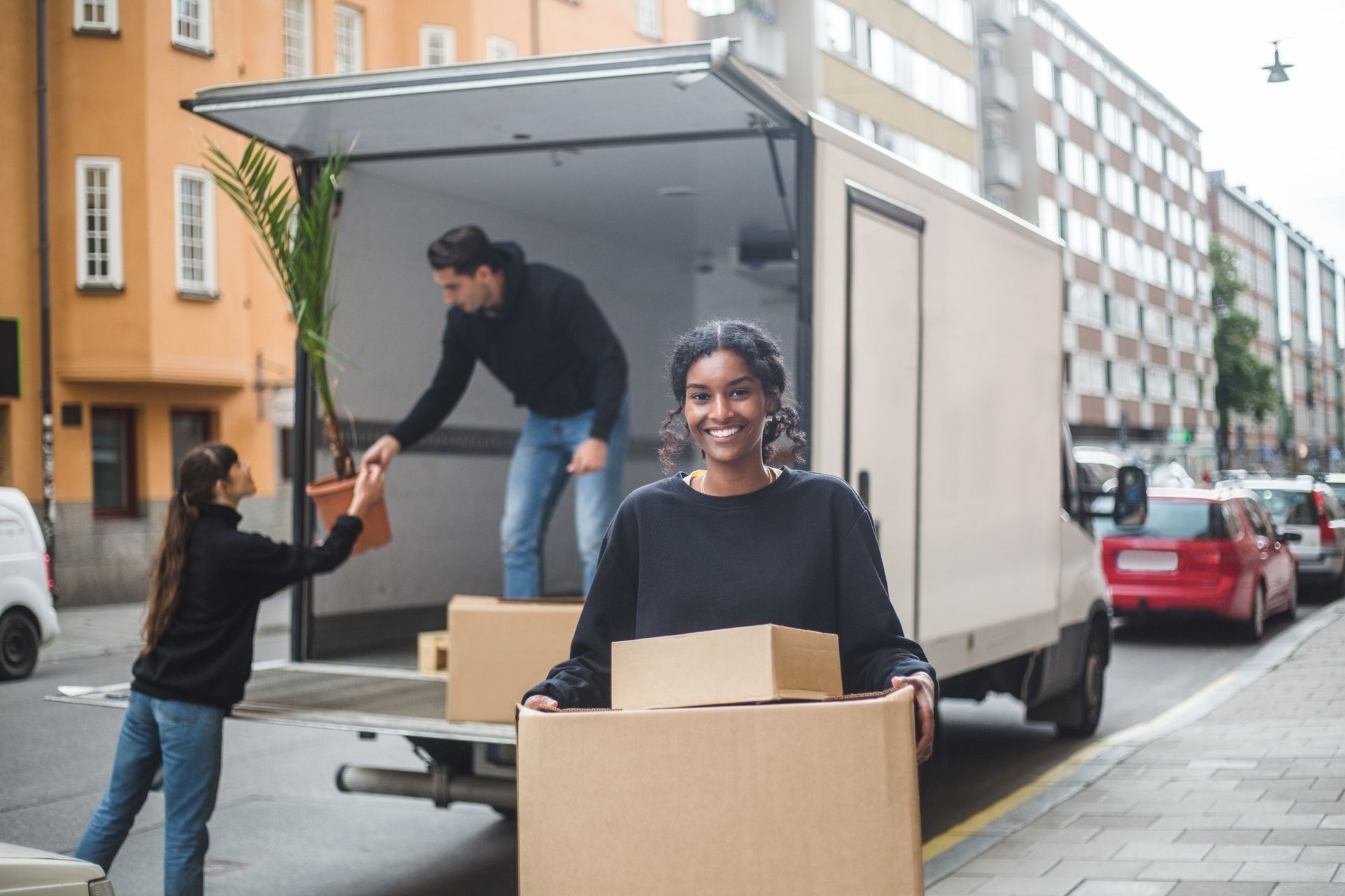 People unloading boxes from truck on city street.