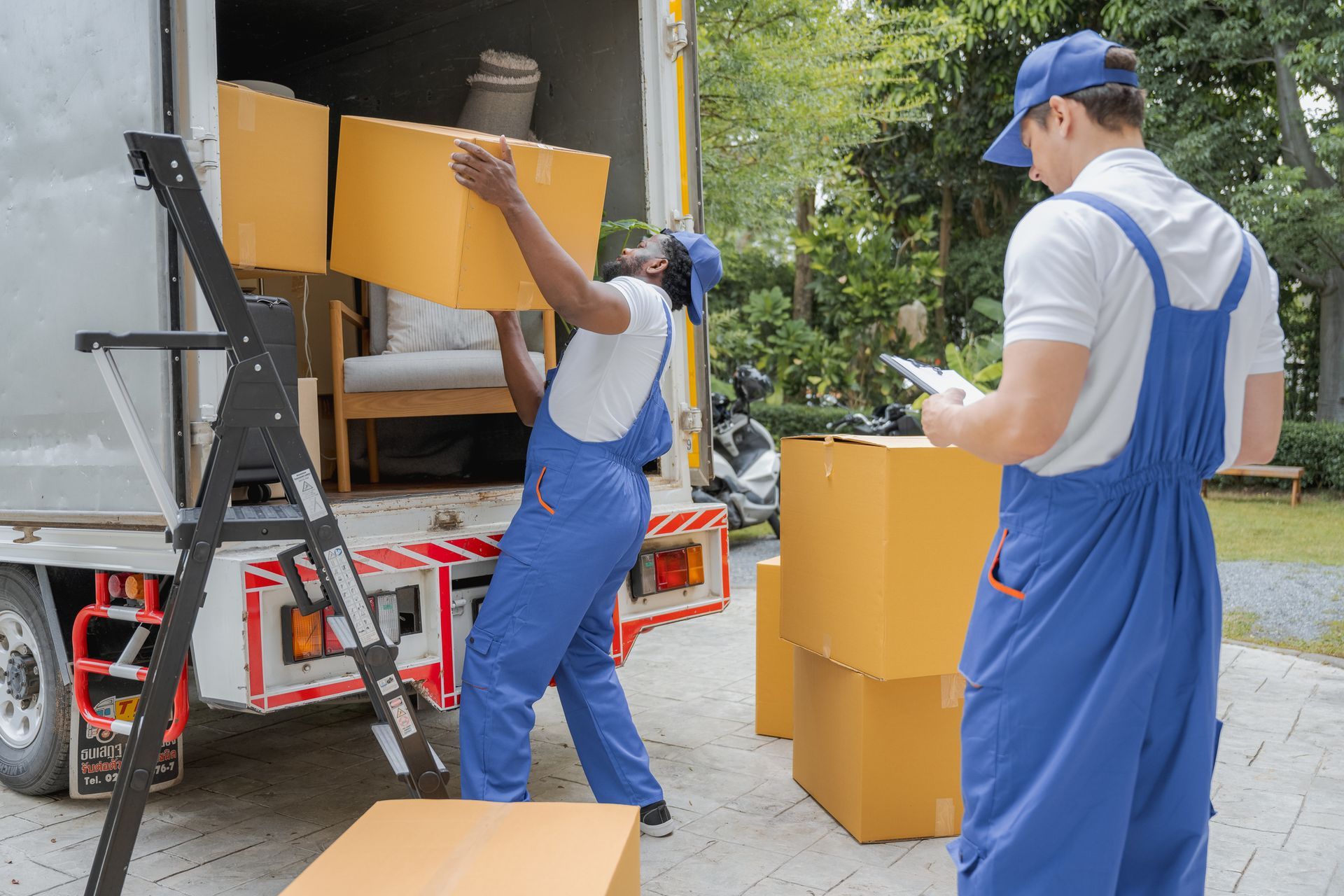 Two movers unload boxes from a truck, highlighting professional residential movers at work. Two movers unload boxes from a truck, highlighting professional residential movers at work.