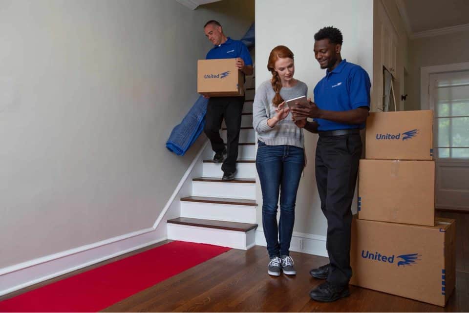 A man and a woman are standing next to a stack of cardboard boxes.