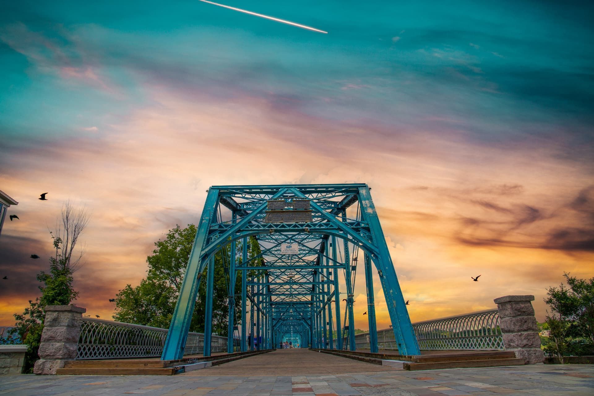 Blue bridge against a sunset sky with streaks of clouds.
