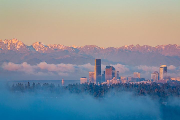 A city skyline covered in fog with mountains in the background.