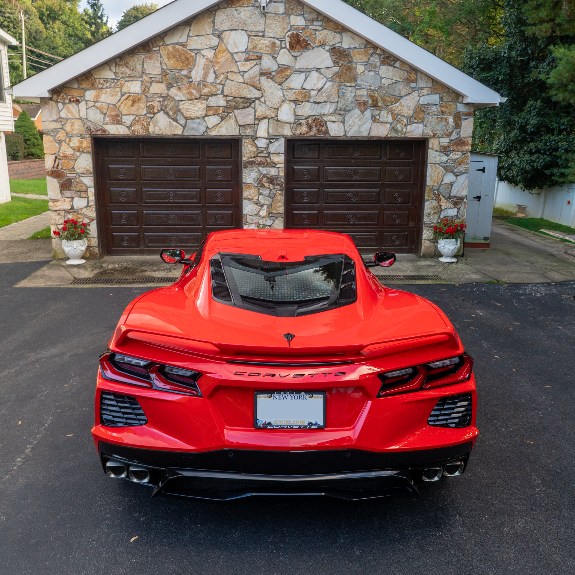 A red sports car is parked in front of a stone garage
