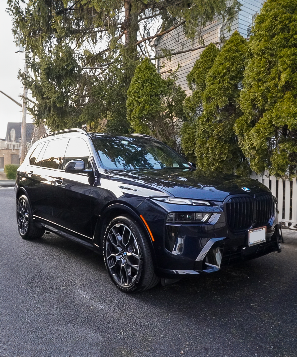 A black bmw x7 is parked on the side of the road.