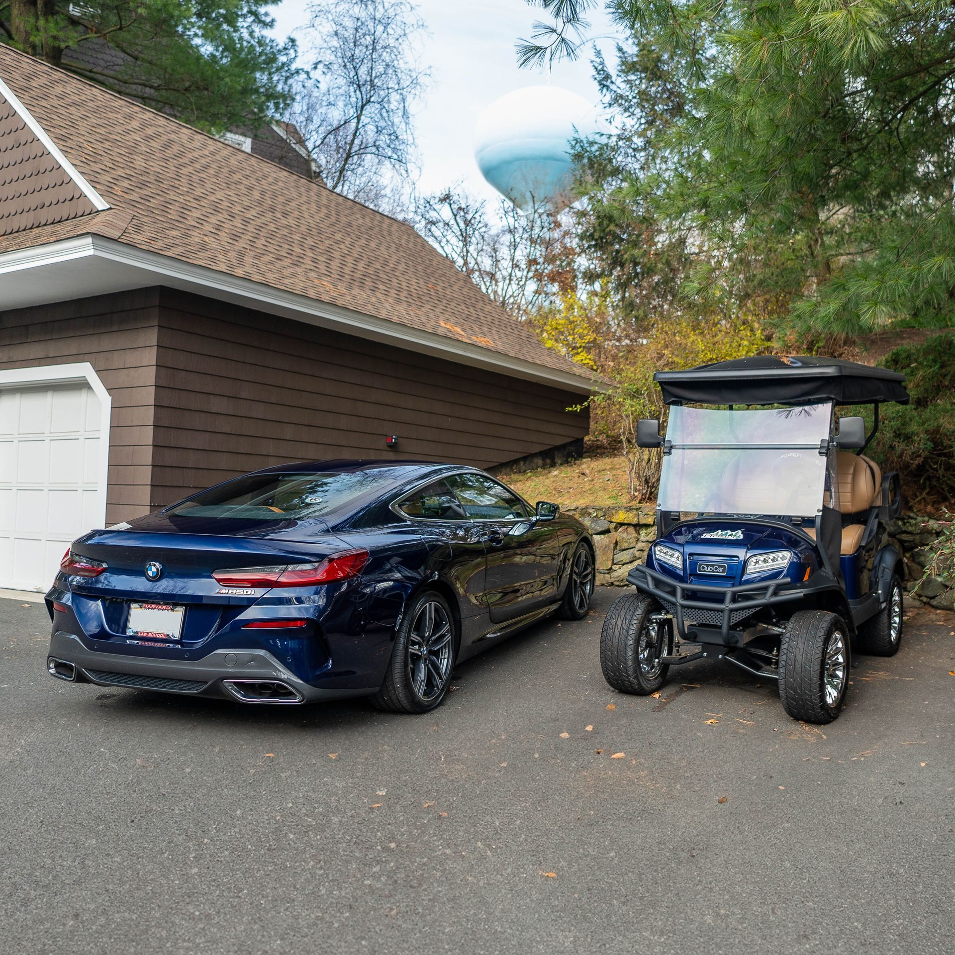 a blue car and a golf cart are parked in front of a garage .