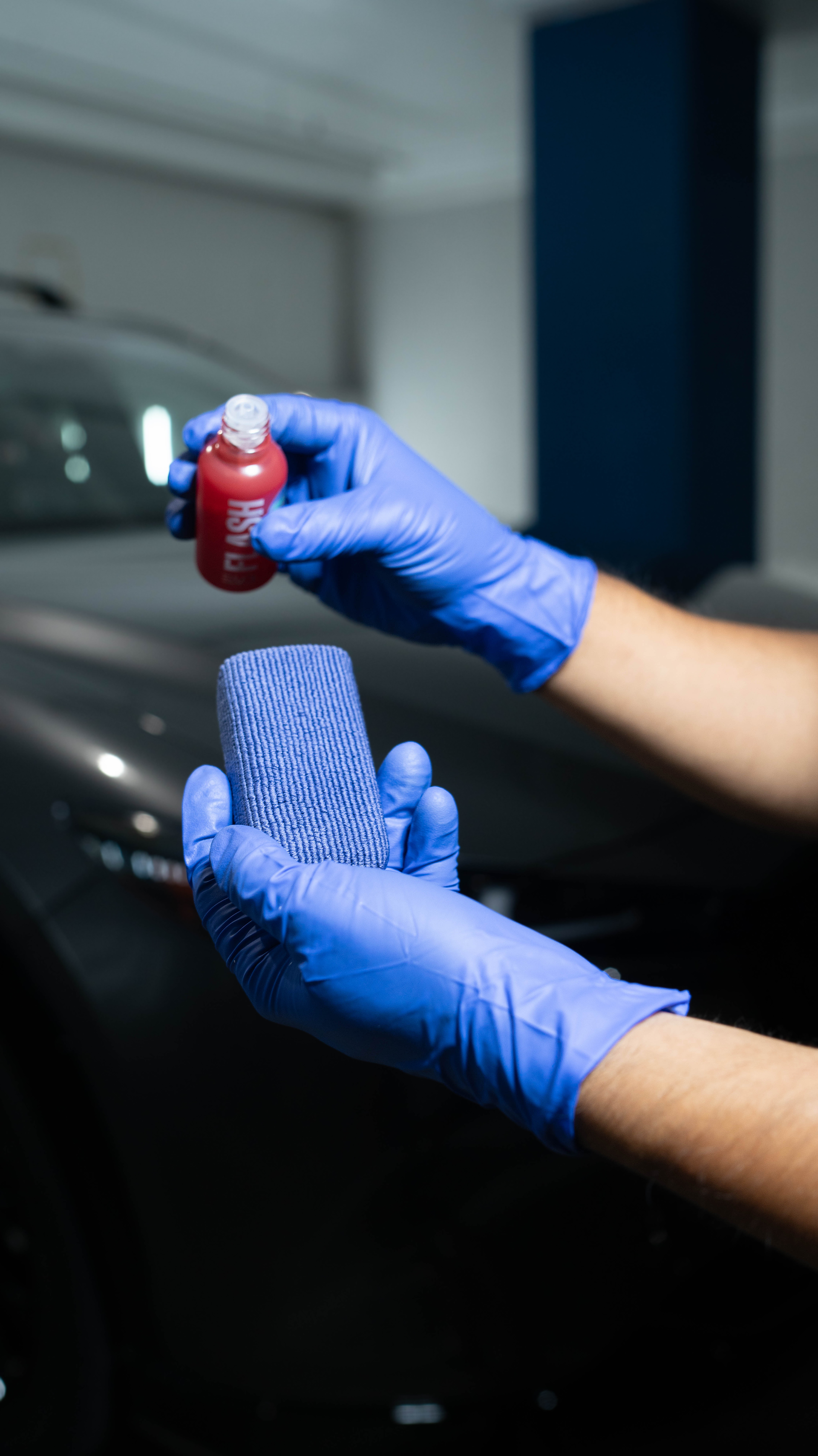Two bottles of polish are sitting next to a red car.