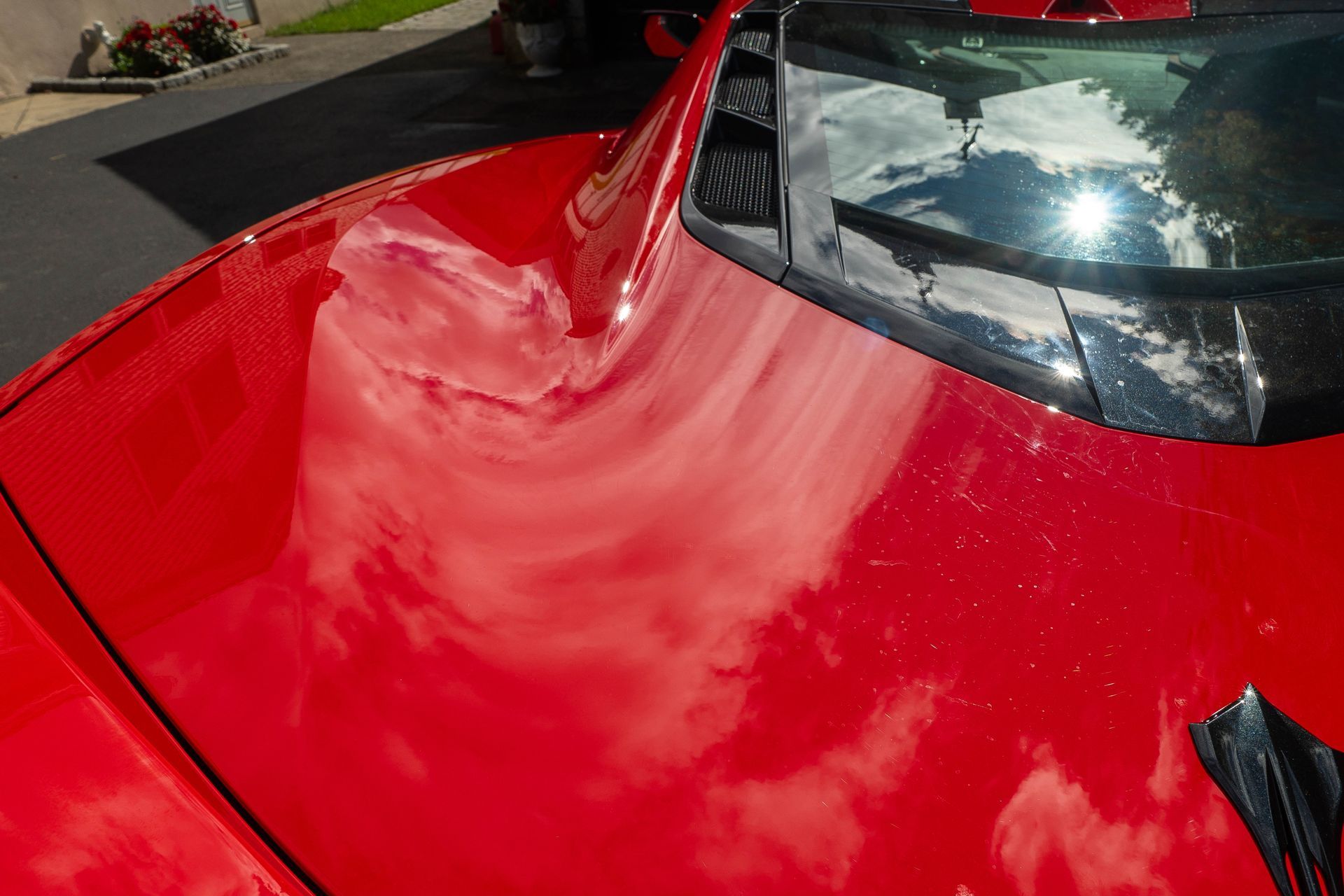 A close up of a red car 's hood and windshield.